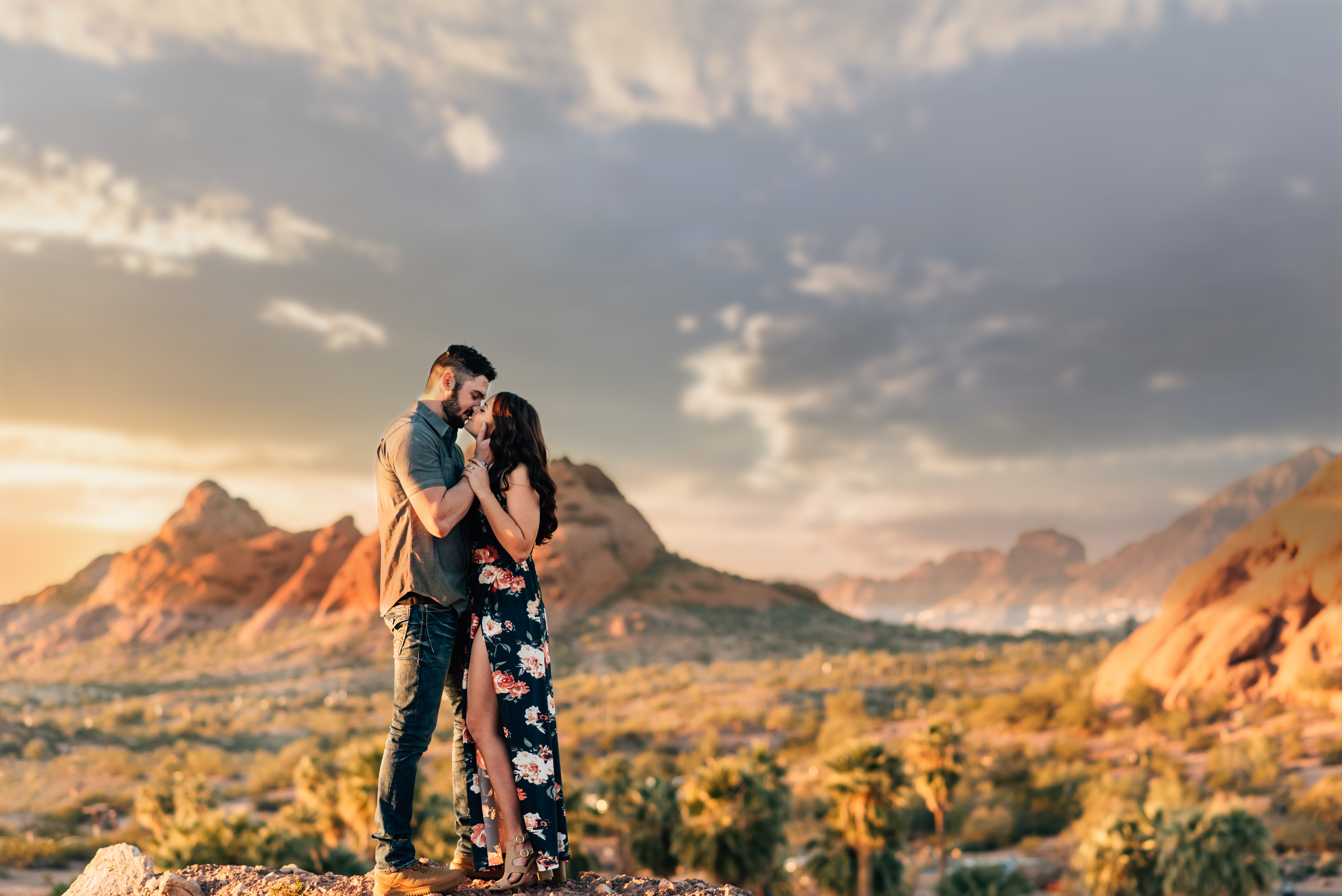 couple kissing while the sun is setting with beautiful red mountain views in the background